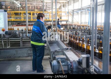 Operator monitors moving empty bottles on conveyor Stock Photo