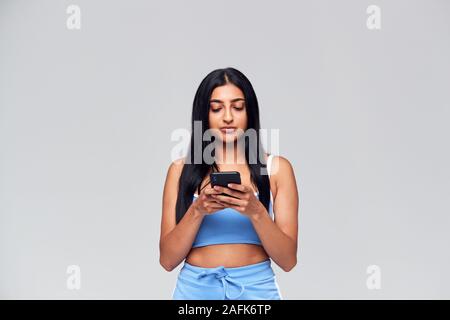 Studio Shot Of Causally Dressed Young Woman Using Mobile Phone Stock Photo