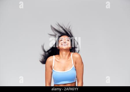Studio Portrait Of Positive Happy Young Woman Flicking Long Hair Stock Photo