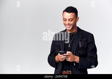 Studio Shot Of Causally Dressed Young Man Using Mobile Phone Stock Photo