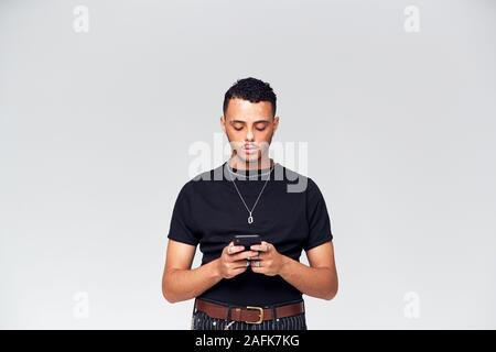 Studio Shot Of Causally Dressed Young Man Using Mobile Phone Stock Photo