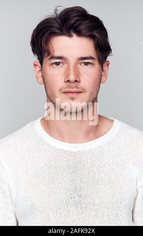 Studio Portrait Of Young Man With Serious Expression Looking At Camera Stock Photo