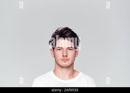 Studio Portrait Of Young Man With Serious Expression Looking At Camera Stock Photo