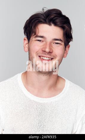 Studio Portrait Of Young Man Wearing White T Shirt Smiling At Camera Stock Photo