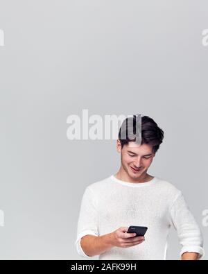 Studio Shot Of Causally Dressed Young Man Using Mobile Phone Stock Photo