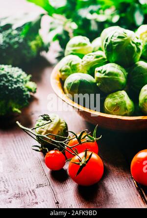 Brussel sprout, cherry tomato, broccoli, parsley and greens on rustic wooden table. Superfood vegetable salad mix on vintage background. Closeup of he Stock Photo
