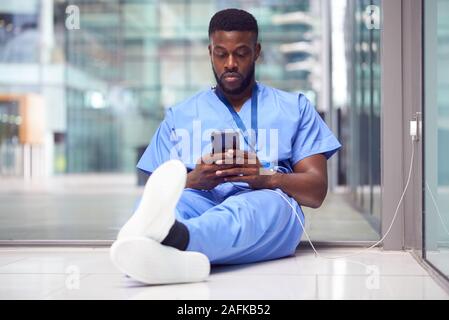 Male Medical Worker In Hospital Addicted To Using Mobile Phone At Work Stock Photo