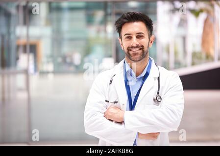 Portrait Of Male Doctor With Stethoscope Wearing White Coat Standing In Modern Hospital Building Stock Photo