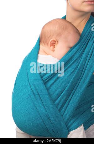 Young mother carrying her little baby in blue sling isolated on white background. Infant is sleeping in comfort, feeling safety and protection Stock Photo