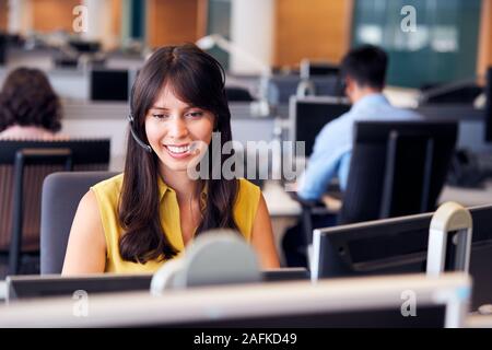 Young Businesswoman Wearing Telephone Headset Talking To Caller In Customer Services Department Stock Photo