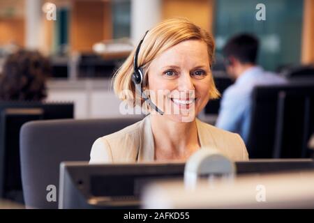 Portrait Of Mature Businesswoman Wearing Telephone Headset Working In Customer Services Department Stock Photo