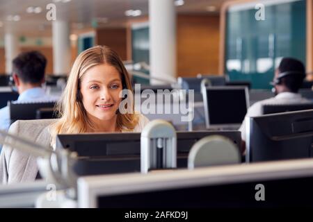 Businesswoman Wearing Telephone Headset Talking To Caller In Customer Services Department Stock Photo