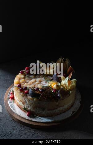 Cheesecake with figs and physalis on a wooden board vertical Stock Photo