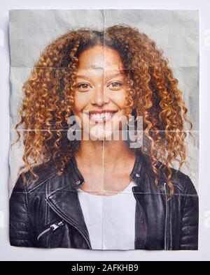 Mental Health Concept With Creased Picture Of Smiling Woman In Studio Stock Photo