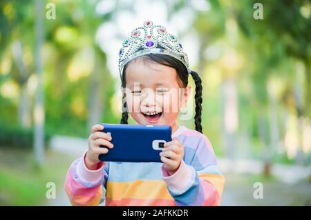 little girl is taking a selfie , When she crowned the princess on head her smile with happy face Stock Photo