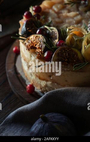 Cheesecake with physalis and dates on a wooden stand close up