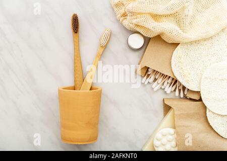 Bamboo toothbrushes in hand made clay glass, soap Cotton Swabs Wooden Sticks,loofah washcloths on white marble background. Natural bath product. Eco f Stock Photo