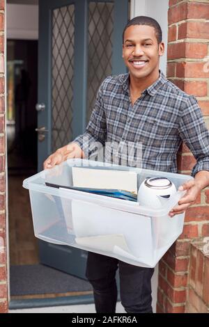 Portrait Of Male College Student Carrying Box Moving Into Accommodation