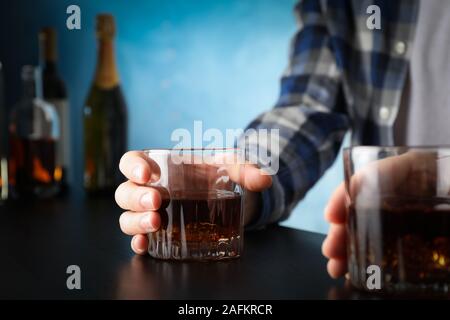 Men holding glasses of whiskey at the bar, space for text Stock Photo