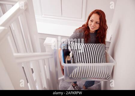 Female College Student Carrying Box Up Stairs Moving Into Accommodation Stock Photo