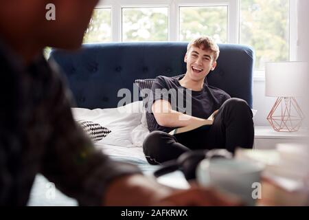 Two Male College Students In Shared House Bedroom Studying And Talking Together Stock Photo