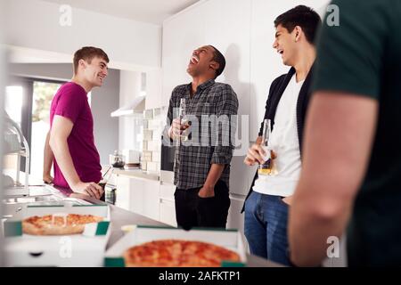 Group Of Male College Students In Shared House Kitchen Drinking Beer And Eating Pizza Together Stock Photo