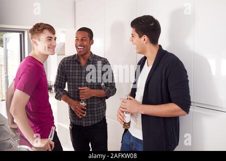 Group Of Male College Students In Shared House Kitchen Drinking Beer Together Stock Photo