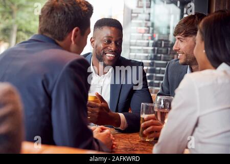 Group Of Business Colleagues Meeting For Drinks And Socializing In Bar After Work Stock Photo