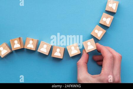 Hand choosing a wooden person block from a set. Employment choice concept Stock Photo