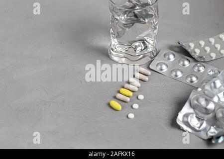 Pills on a gray background. Near a glass of water. Records with medicines. Stock Photo