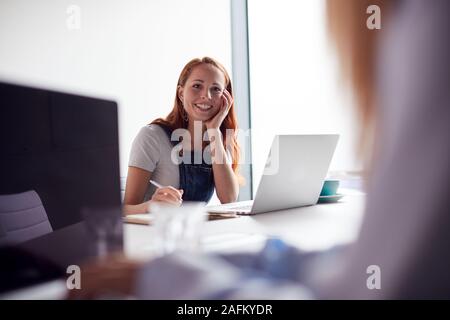 Two Casually Dressed Young Businesswomen Working On Laptops In Modern Meeting Room