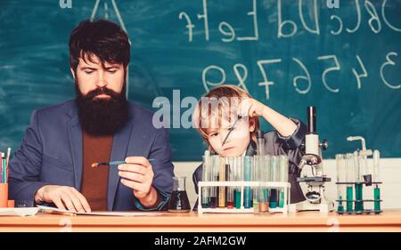 teacher man with little boy. school lab equipment. Back to school. father and son at school. using microscope in lab. student doing experiments with microscope in lab. Education is the ray of light Stock Photo