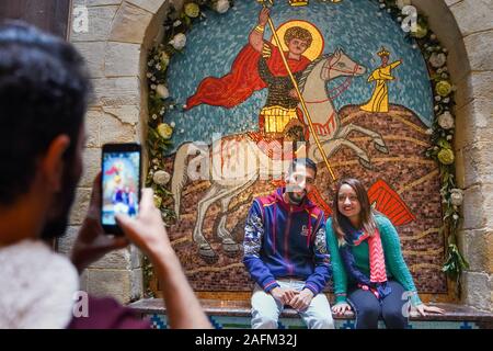 Young people take photos in front of a mosaic in St. George's Church in the Coptic old town of Cairo, Egypt Stock Photo