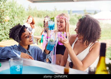 Female Friends Buying Drinks From Bar At Music Festival Making A Toast Stock Photo