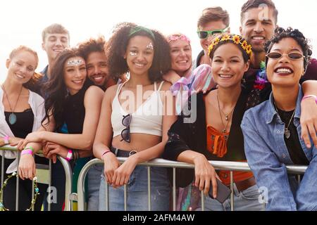 Portrait Of Young Friends In Audience Behind Barrier At Outdoor Music Festival Stock Photo