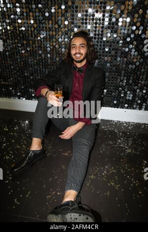 Young elegant man in suit toasting with champagne while sitting on the floor Stock Photo