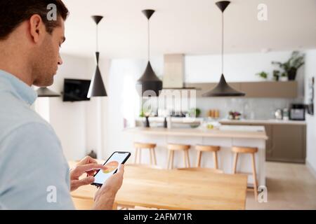 Man Using App On Smart Phone To Control Central Heating Temperature In House Stock Photo