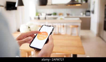 Close Up Of Man Using App On Smart Phone To Control Central Heating Temperature In House Stock Photo