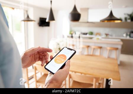 Close Up Of Man Using App On Smart Phone To Control Central Heating Temperature In House Stock Photo
