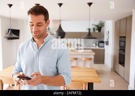 Man Using App On Smart Phone To Control Central Heating Temperature In House Stock Photo
