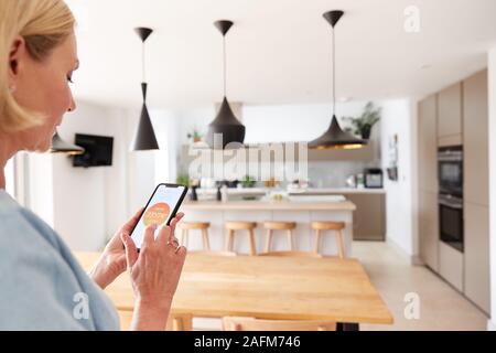 Close Up Of Woman Using App On Smart Phone To Control Central Heating Temperature In House Stock Photo
