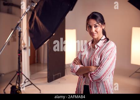 Portrait Of Smiling Female Photographer Standing In Studio With Lighting Equipment Stock Photo