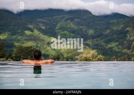 Man relaxing in swimming pool on the central highlands in Sri Lanka Stock Photo