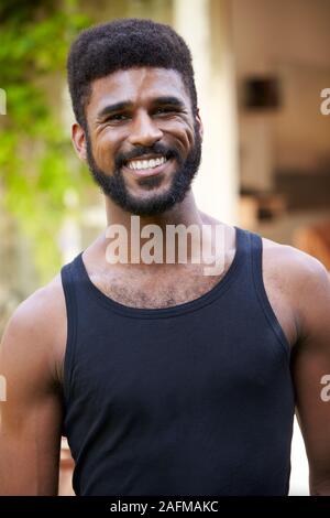Portrait Of Smiling Man At Home In Garden Against Flaring Sun Stock Photo