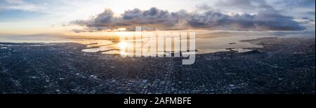 A serene sunset illuminates the densely populated San Francisco Bay area including Oakland, Berkeley, Emeryville, El Cerrito, and San Francisco. Stock Photo