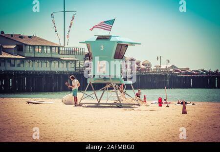 People on East beach near Sterns Wharf at the Aqua blue lifeguard stand in Santa Barbara, CA, USA Stock Photo