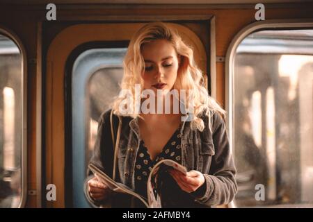 Young woman reading magazine while traveling in subway train Stock Photo