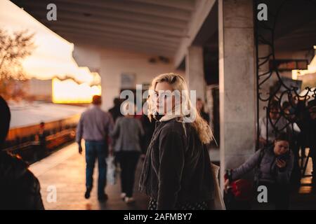 Young woman looking back at camera walking on subway station Stock Photo