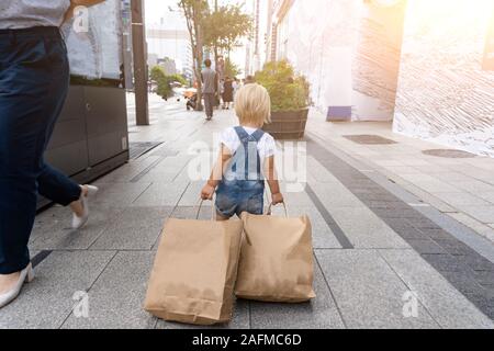 Child is carring bags after black Friday sale. Stock Photo