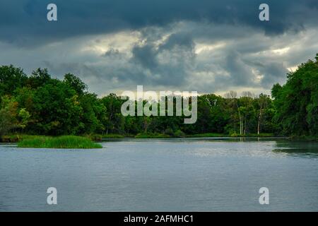 Storm dramatic clouds over a quiet forest lake. Gloomy clouds. Soft focus Stock Photo